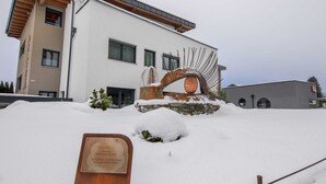 Ein modernes Gebäude mit verschneitem Eingang und einer Metallskulptur.