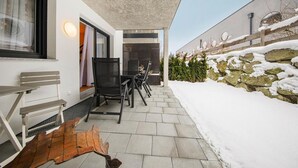 Eine moderne Außenpatio mit einer Steinmauer, einer Holzbank und einer Sitzgruppe mit Stühlen.