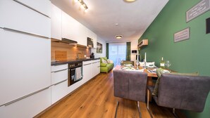 Eine moderne Küche mit weißen Schränken, einer Holzausziehtafel und einem Essbereich mit Tisch und Stühlen.