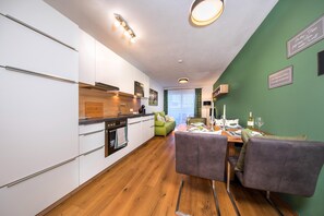 Une cuisine moderne avec des meubles blancs, un plan de travail en bois et un coin repas comprenant une table et des chaises.