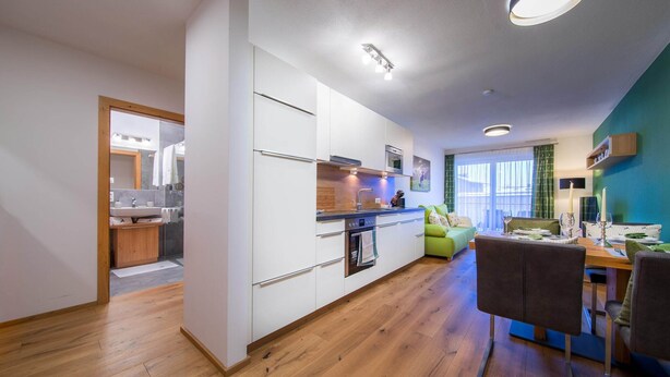 Eine moderne Küche mit weißen Schränken, einer Holz Arbeitsplatte und einem Essbereich mit Tisch und Stühlen.