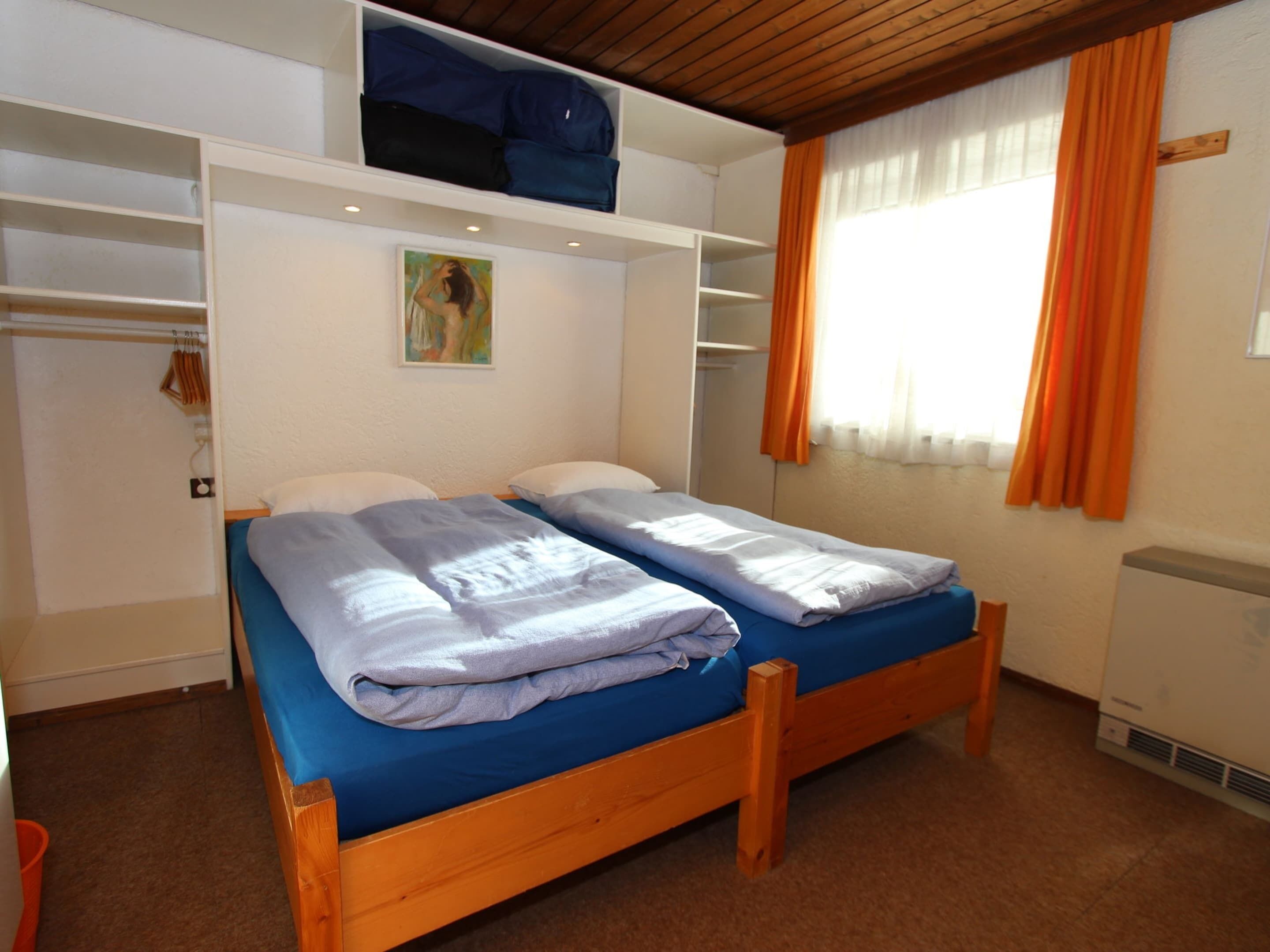 Un dormitorio con dos camas, un armario y un cuadro en la pared.