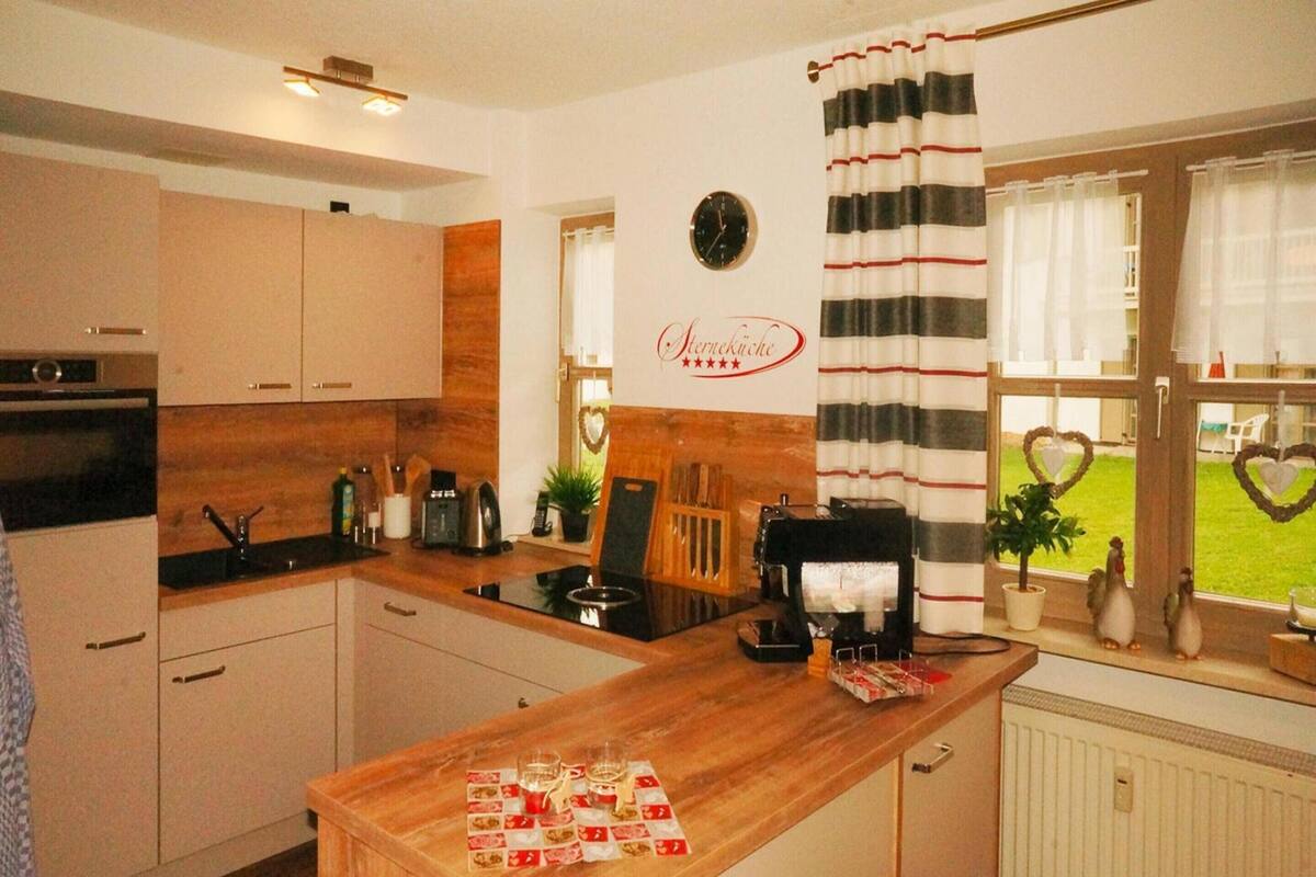 A modern kitchen with wooden cabinets, a coffee machine, and a breakfast bar.