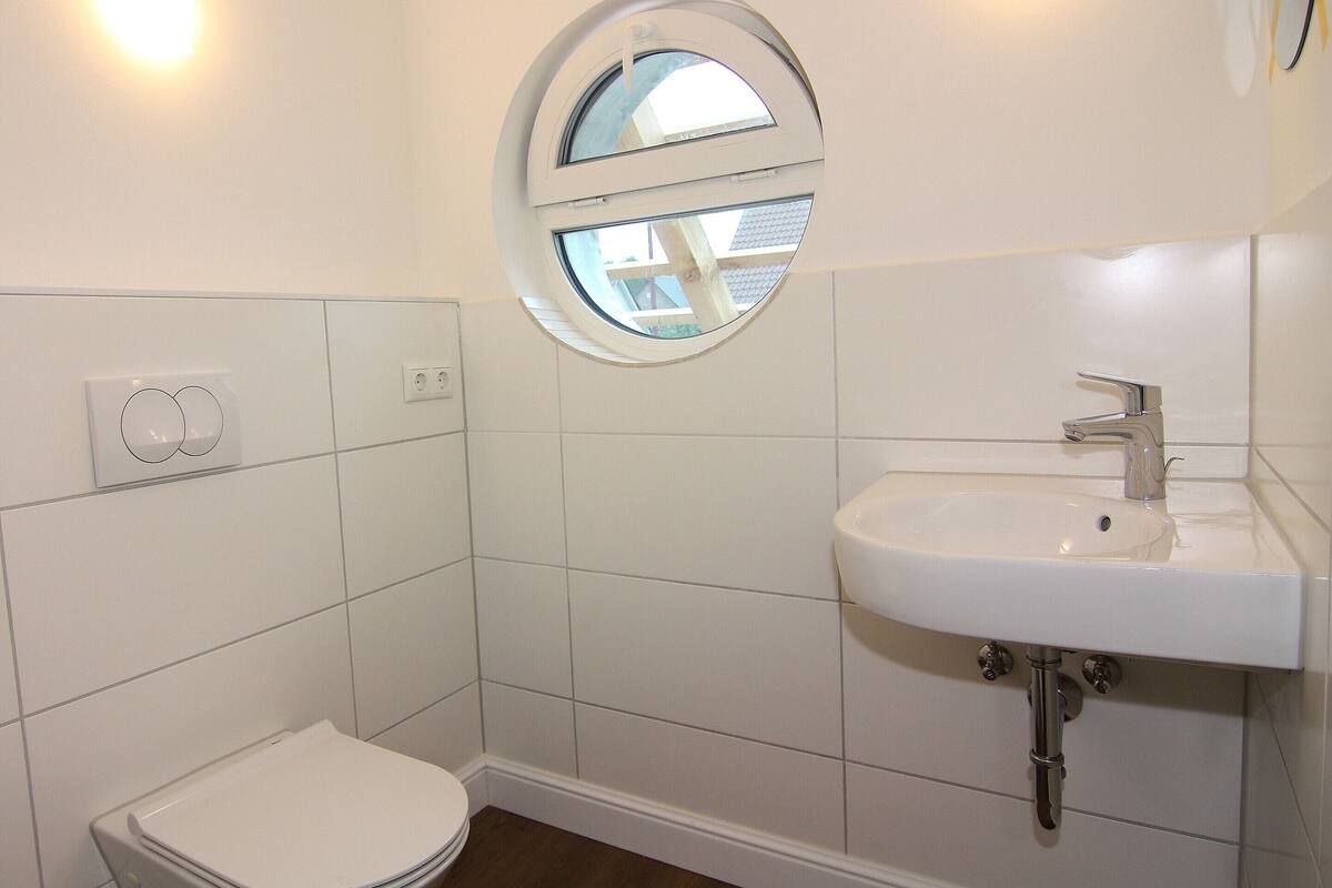 A small, clean bathroom with a toilet, sink, and a window.