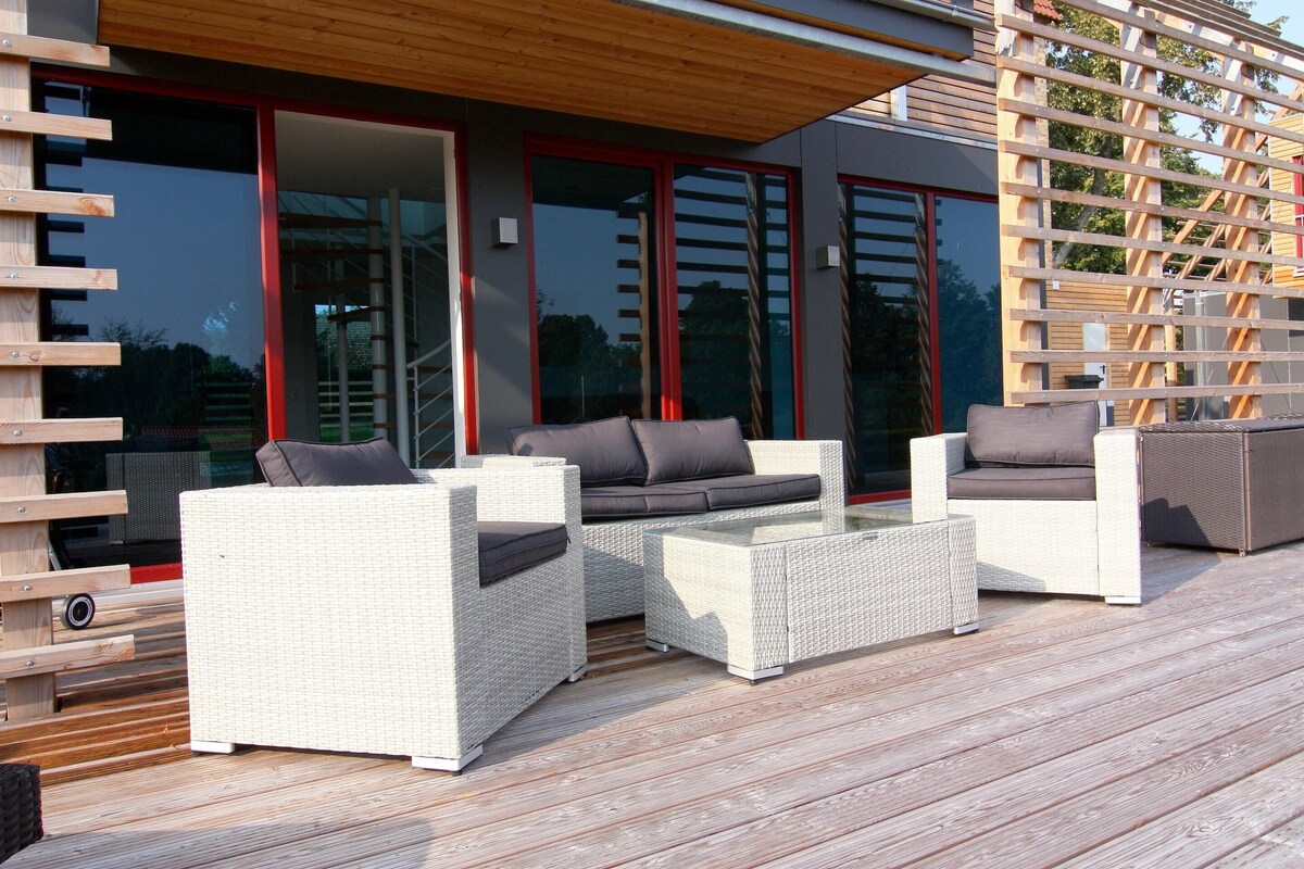 A deck with wicker furniture, including sofas and a coffee table.
