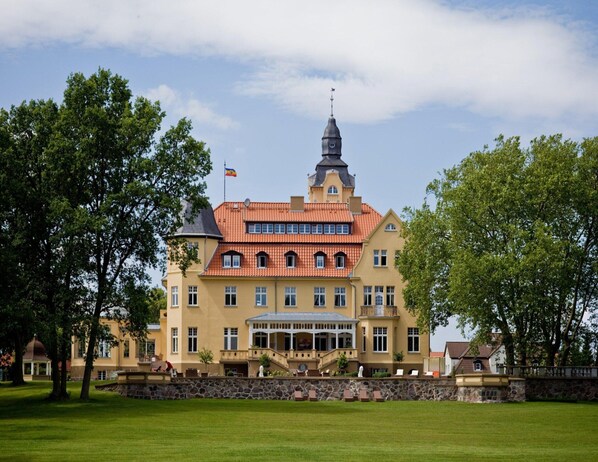 Ein großes, gelbes Gebäude mit rotem Ziegeldach, einem markanten Turm und einer Flagge.