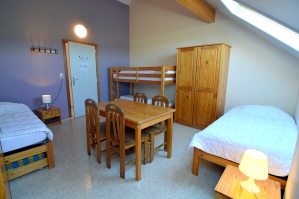 A dormitory room with bunk beds, a wooden table with chairs, a cabinet, and a desk lamp. - Contemporary House in Rendeux With Indoor Pool (Rendeux)