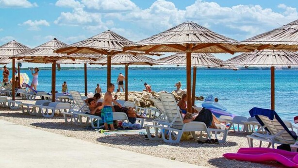 A beach with sun loungers and thatched umbrellas. - Apartments in House Liveric, in Vir at the Beach (Vir)