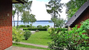 A brick building with a number '15' on the wall, a grassy yard, and a view of a lake.