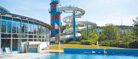 Ein Schwimmbecken mit Wasserrutsche und einem hohen Turm.