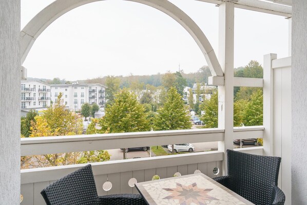 Un balcon avec vue sur les immeubles et les arbres.