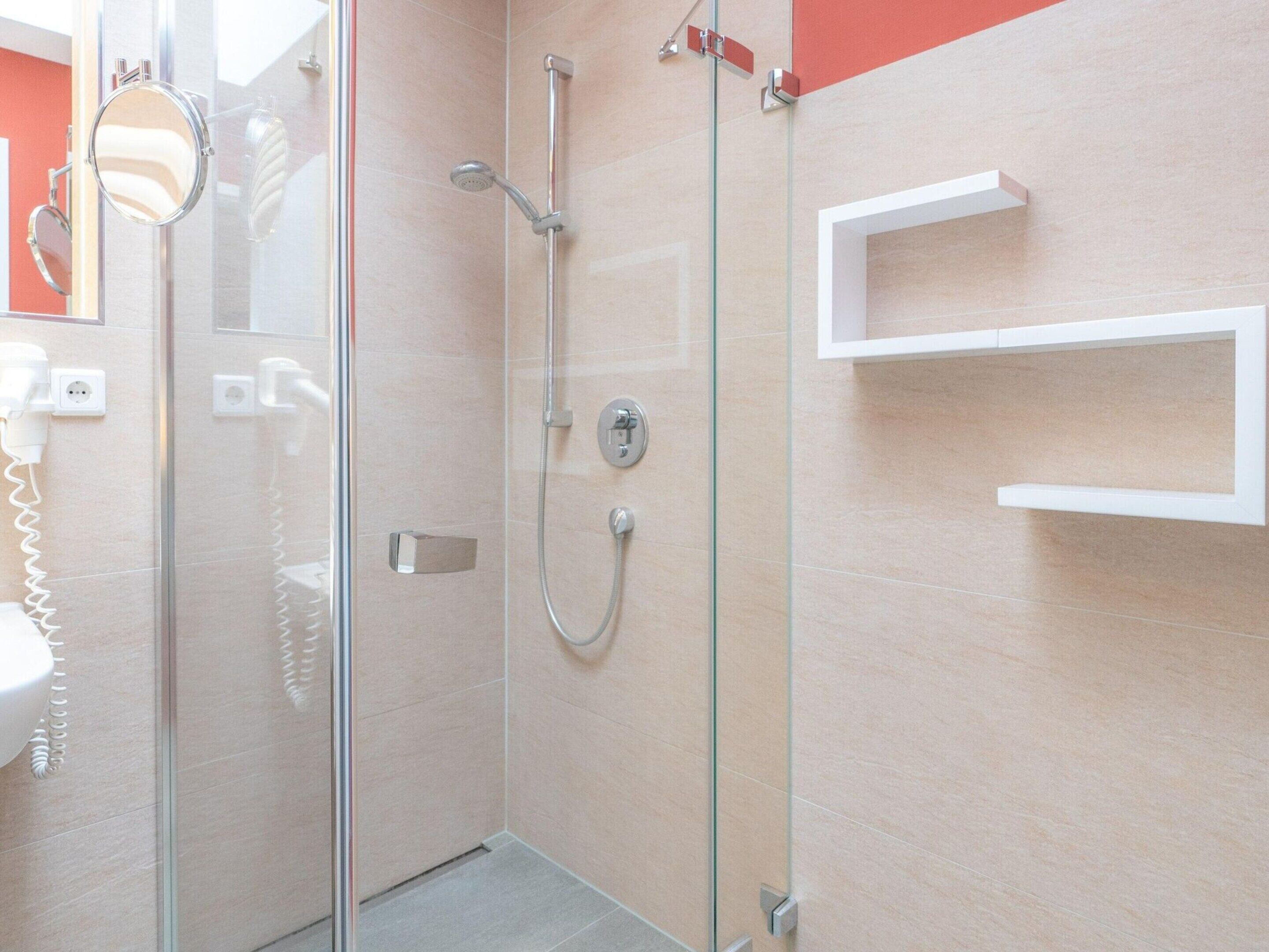 Une salle de bain moderne avec une douche à parois de verre, un lavabo blanc et un miroir.