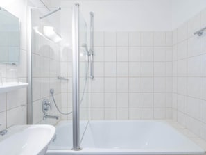 A modern bathroom with a glass-enclosed shower, a white sink, and a bathtub.