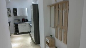 Eine moderne Küche mit weißen Schränken, einer Kaffeemaschine und einem Holzkasten mit Haken.