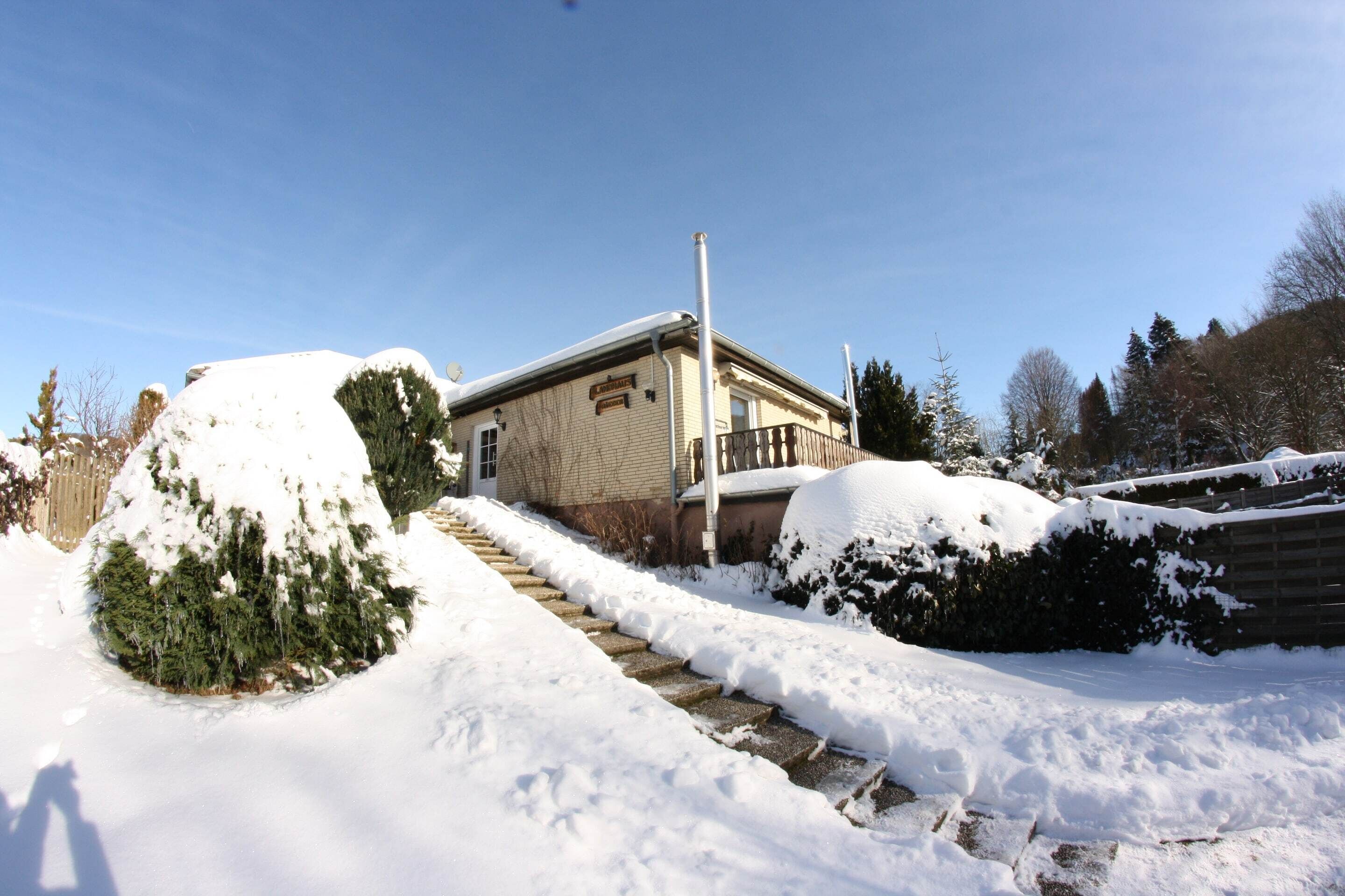 A snow-covered house with a visible front porch and a mailbox.
