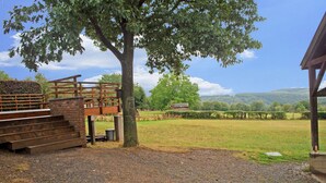 A rustic outdoor area with a wooden staircase leading up to a platform, surrounded by a large tree and a grassy field. - Beautiful Gite in Jalhay 5 Minutes From the Hautes Fagnes (Jalhay)
