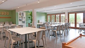 A spacious dining area with multiple tables and chairs, large windows with a view of greenery, and a green wall with framed pictures. - Beautiful Gite in Jalhay 5 Minutes From the Hautes Fagnes (Jalhay)