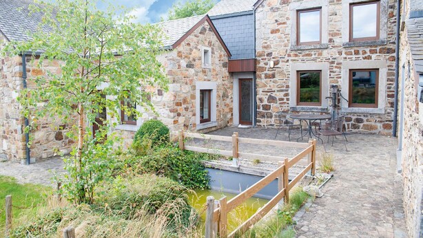 A stone building with a wooden deck and a small pond. - Beautiful Gite in Jalhay 5 Minutes From the Hautes Fagnes (Jalhay)