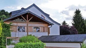 A two-story house with a sloped roof, wooden beams, and large windows. - Beautiful and Cosy Apartment in a Wooded and Mostly Quite Rustic Ambience (Balesfeld)