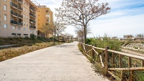 A paved walkway flanked by a wooden fence and a yellow building with balconies. - Beautiful and Cosy Apartment in a Wooded and Mostly Quite Rustic Ambience (Balesfeld)