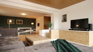Un salon moderne avec un canapé, une table basse et un téléviseur posé sur un meuble.