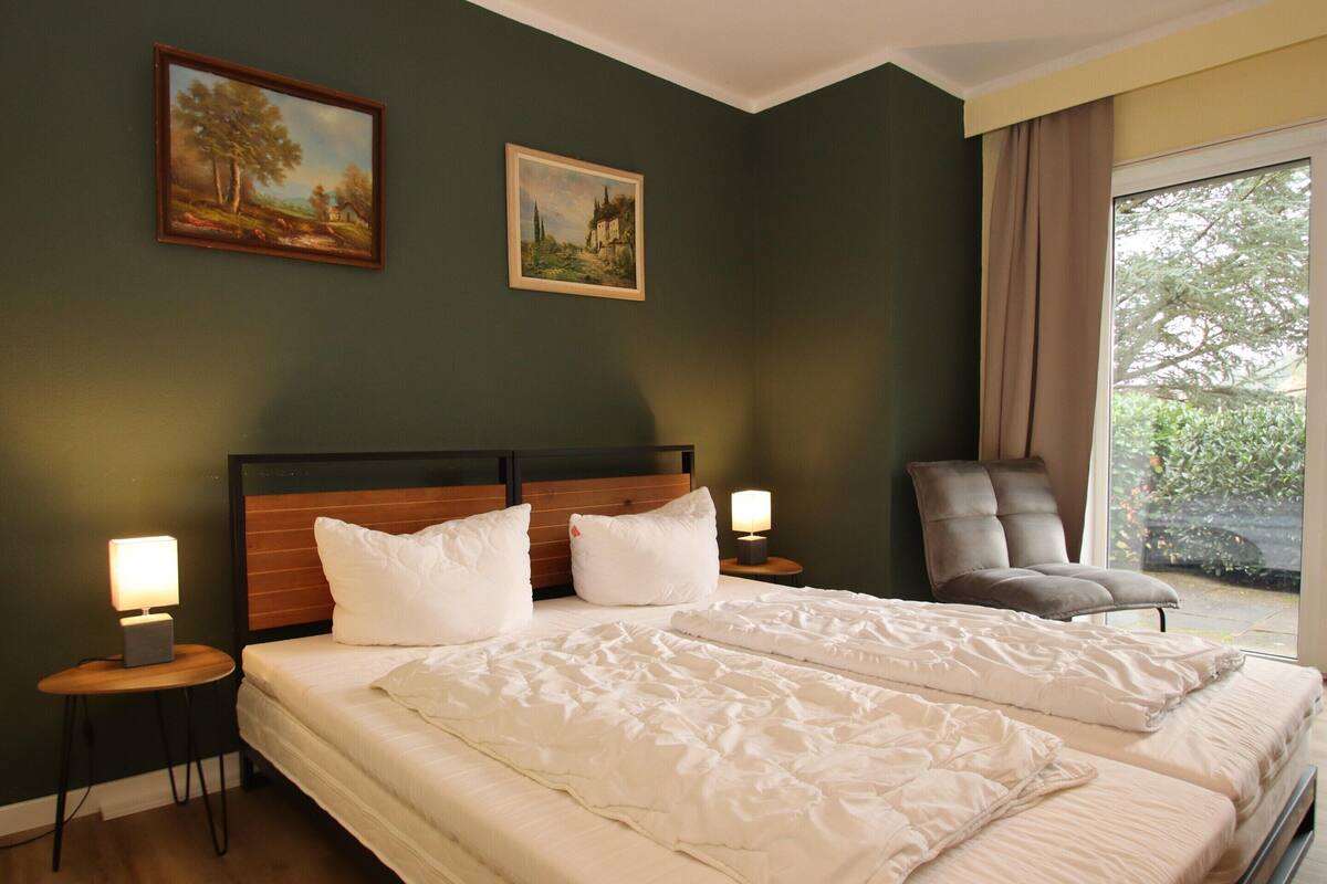 Une chambre d’hôtel avec deux lits, une chaise et deux tableaux accrochés au mur.