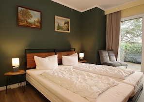 A hotel room with two beds, a chair, and two paintings on the wall. - Ferienwohnung mit Weitem Ausblick in Altenau (Clausthal-Zellerfeld)