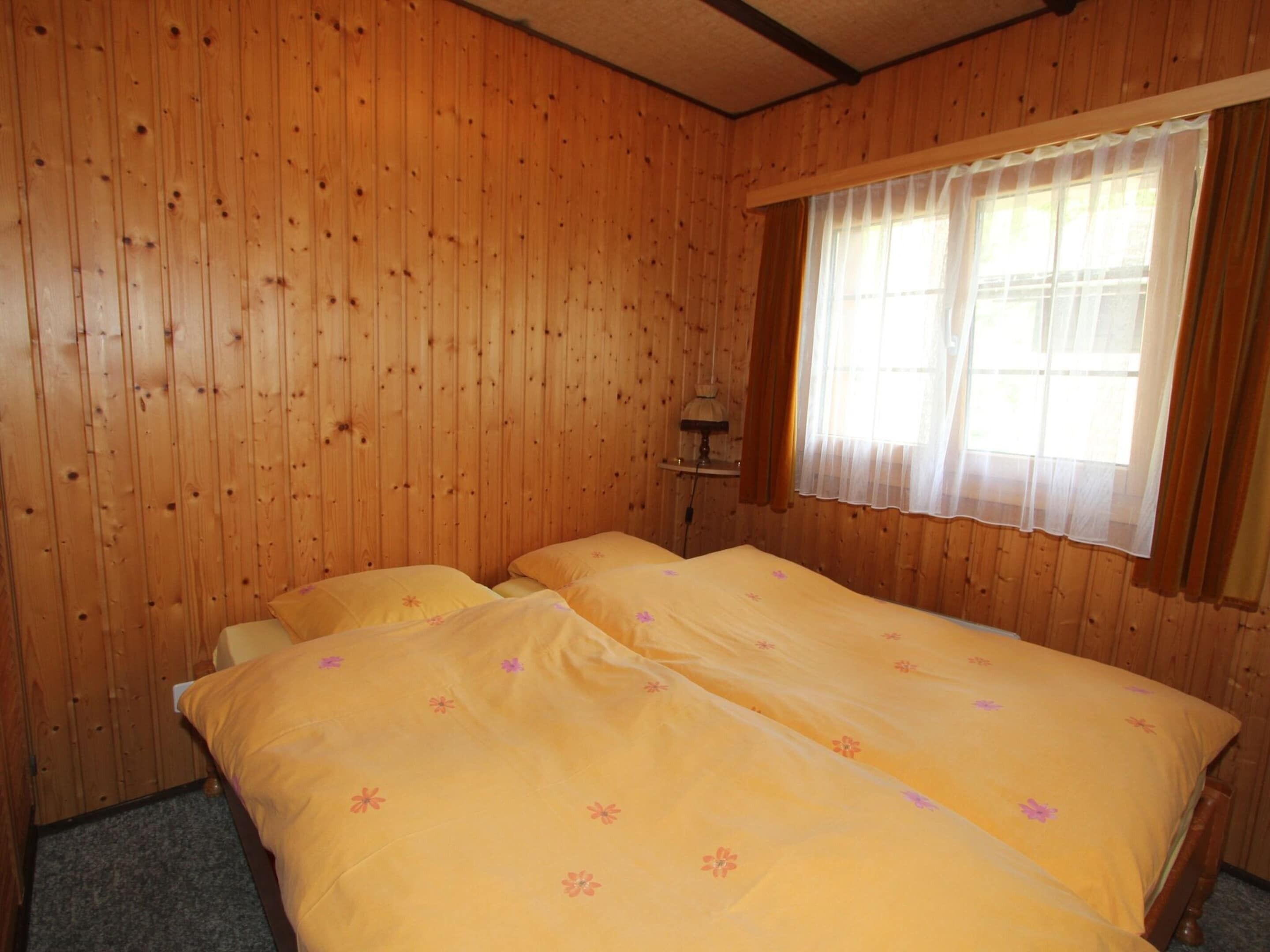 A room with wooden walls and a large bed with floral bedding.