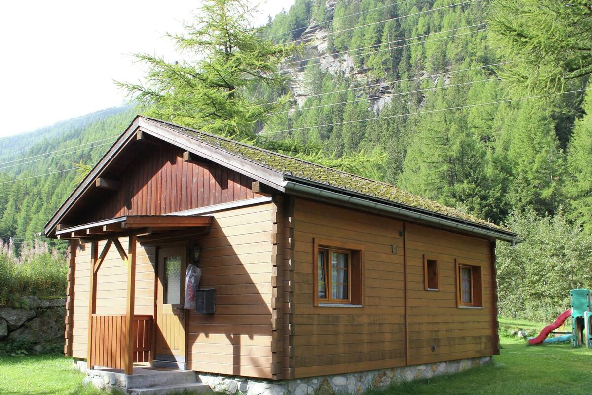 A wooden cabin with a sloped roof, a front porch, and a small window.