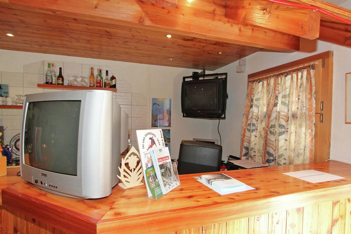 A wooden reception desk with a television, a shelf with bottles, and a poster.