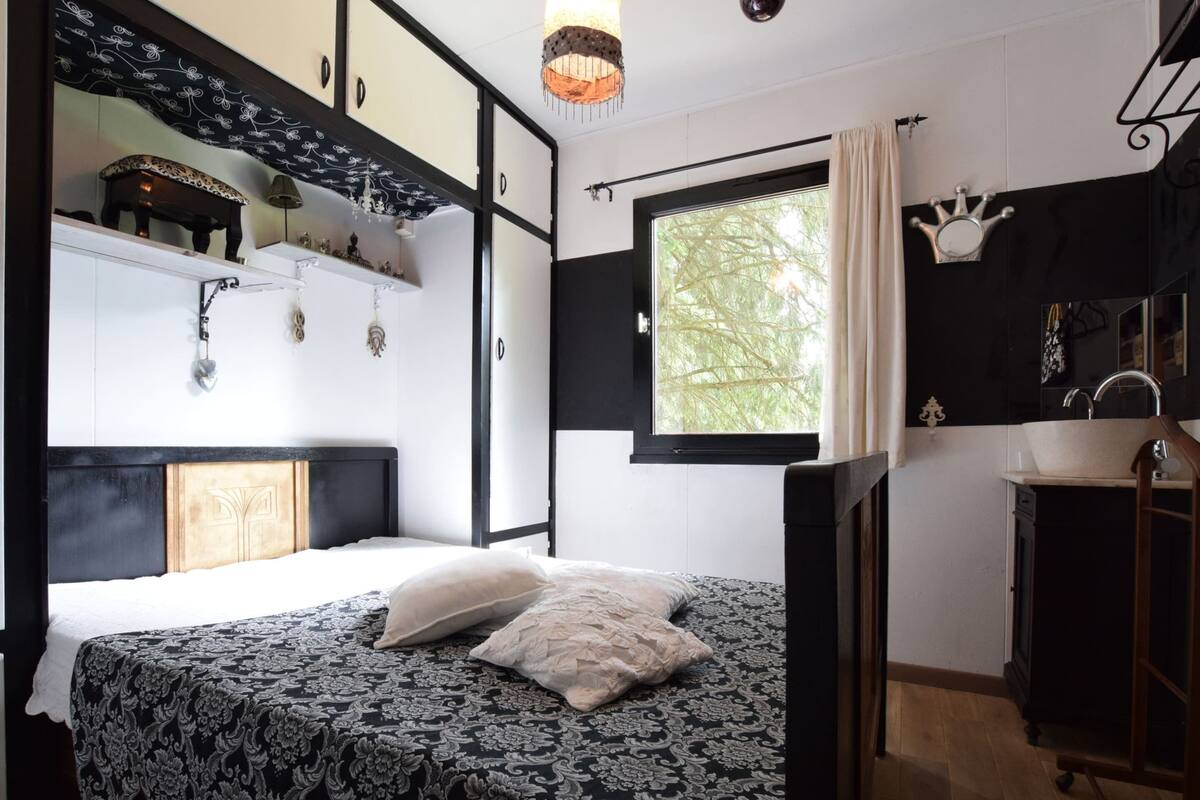 A bedroom with a bed, a window with a view, a sink, and a cabinet.
