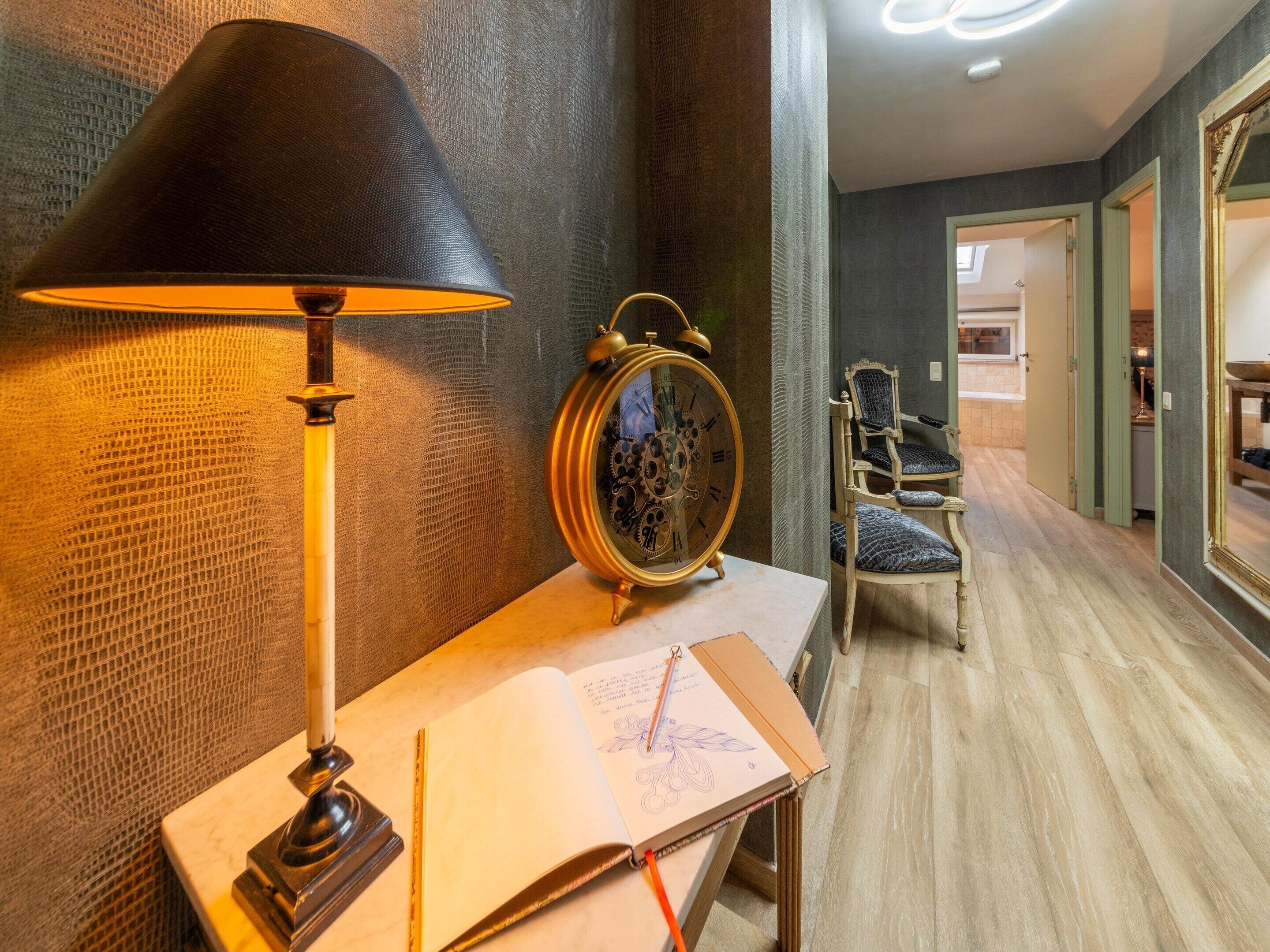 A study area with a desk, lamp, and an open book with a pencil.