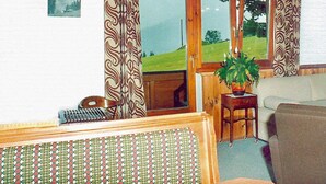 Ein gemütliches Wohnzimmer mit einem Holztisch, einer Couch und einem Fenster mit Vorhängen.