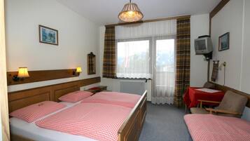 Habitación de hotel con una cama grande, dos mesitas de noche, un escritorio con silla, televisor y una ventana con cortinas.