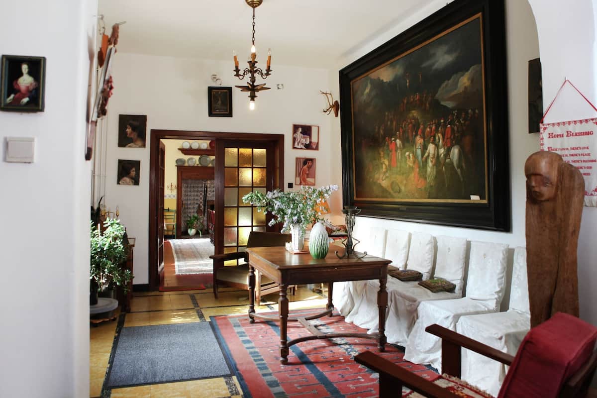 A traditional living room with a large painting, a chandelier, and a red armchair.
