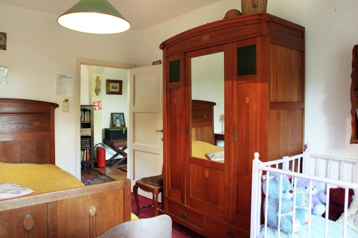 A cozy space with a traditional wardrobe, bed, and crib, perfect for families.