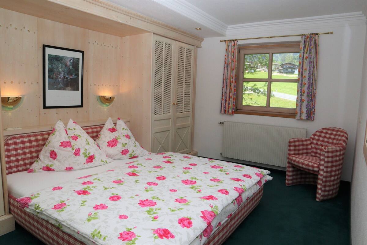 Ein Schlafzimmer mit einem Bett, einem Sessel, einem Fenster und einer Tür.