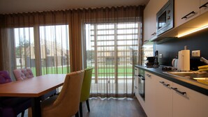 A modern kitchen with a dining area, large windows, and a view of a green lawn. - Chalet, Wendorf (Kuhlen-Wendorf)