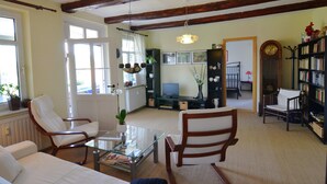 A living room with a sofa, chairs, a coffee table, a television, and a bookshelf. - Modern Apartment in a Listed Villa With Beautiful View From Balcony (Quedlinburg)
