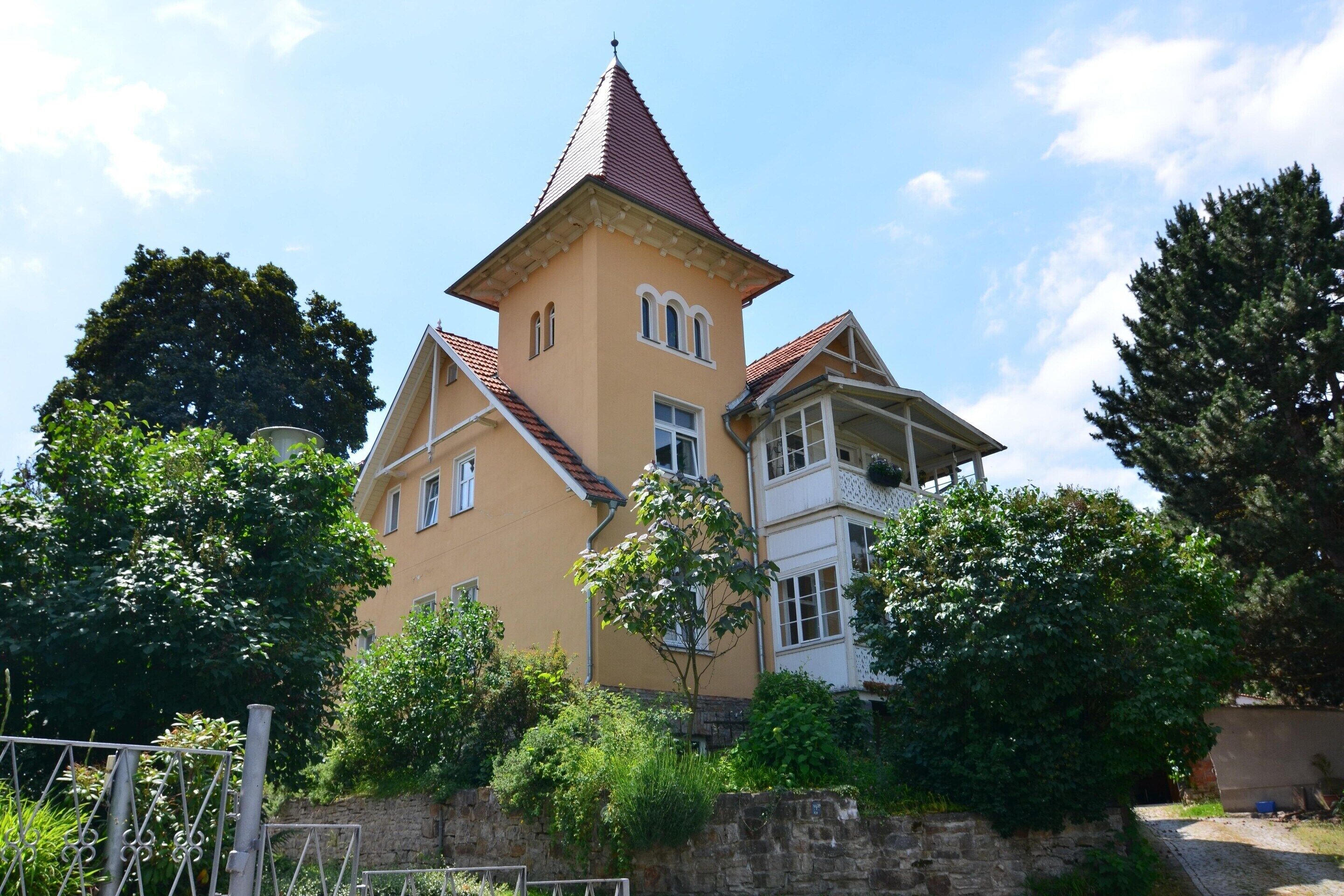 Un grande edificio a più piani con una torre imponente e un tetto in tegole rosse.