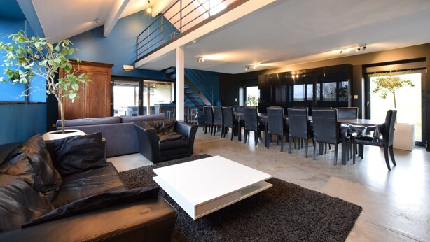 A spacious living area with a sofa, coffee table, and dining area with chairs. - Modern Cottage in Vaux-sur-sure With Sauna (Vaux-sur-Sure)