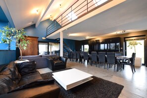 A spacious living area with a sofa, coffee table, and dining area with chairs. - Modern Cottage in Vaux-sur-sure With Sauna (Vaux-sur-Sure)
