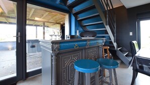 A bar area with a counter, stools, and a staircase. - Modern Cottage in Vaux-sur-sure With Sauna (Vaux-sur-Sure)