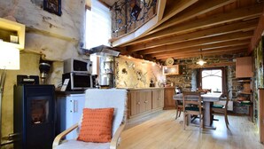 Una cocina rústica con vigas de madera, una pared de piedra y un comedor con mesa y sillas de madera.