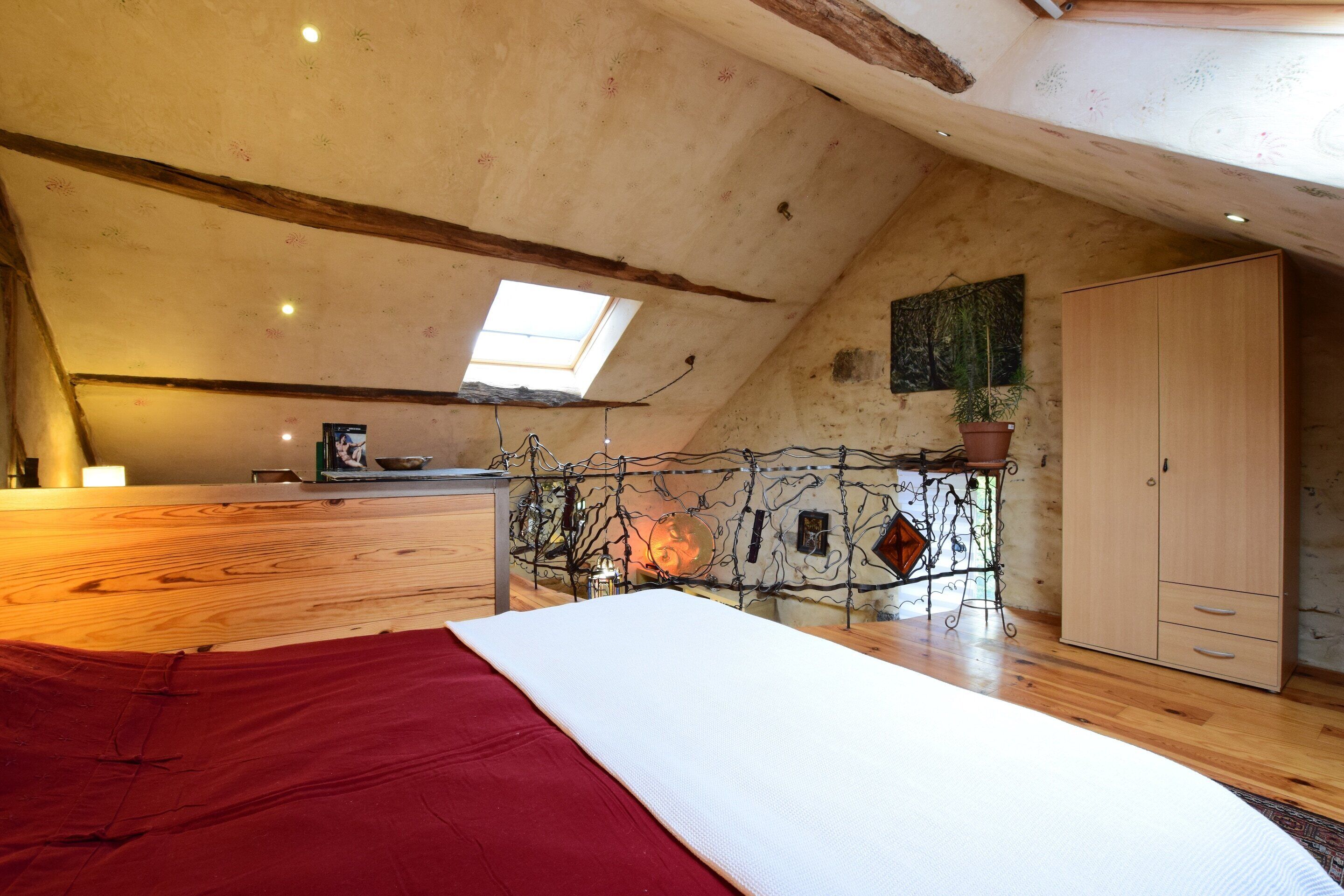Camera da letto con soffitto spiovente, una cupola luminosa, un letto, un armadio e una parete decorativa.