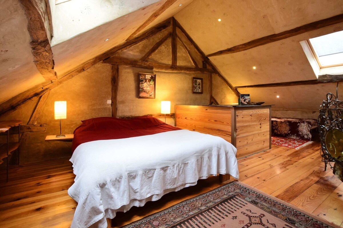 Ein gemütliches Schlafzimmer im Dachgeschoss mit einem Holzbett, einer roten Decke und einem Oberlicht.