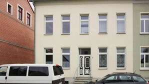 A two-story building with a beige facade, multiple windows, and a door with a number '5' sign. - Apartment in Malchow With Terrace (Malchow)