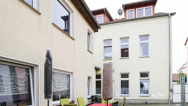 An outdoor patio with a table and chairs, a covered area, and a building in the background. - Apartment in Malchow With Terrace (Malchow)