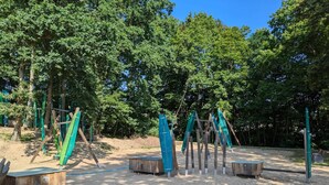A playground with swings and climbing structures in a wooded area. - Apartment in Malchow With Terrace (Malchow)