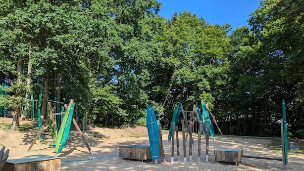 A playground with swings and climbing structures in a wooded area. - Apartment in Malchow With Terrace (Malchow)
